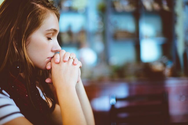 Woman praying during pastoral prayer in the Seventh-Day Adventist Church during Divine hour service on Sabbath morning