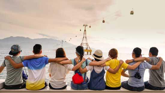 People sitting along the seashore with arms around each other, showing the love that Christians have for another