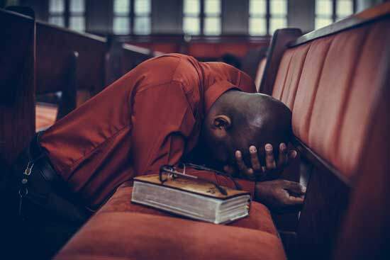 Man kneeling at the pew, praying in repentance under the conviction of the Holy Spirit, surrendering His life to God