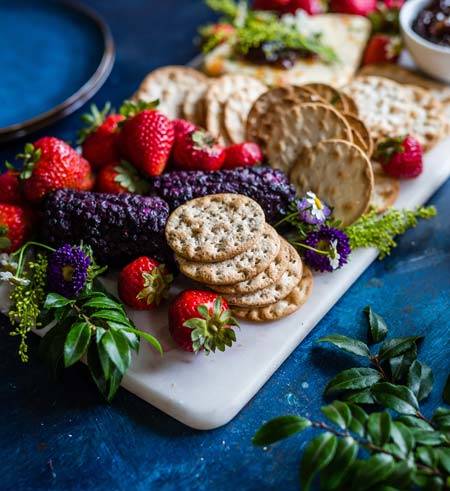 Strawberry & biscuits with blue flowers & green leaves on a white cutting board on blue tablecloth - AAAF