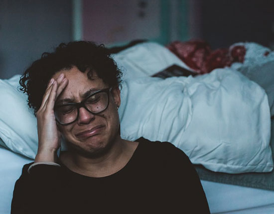 Woman grieving with hand up to face, eye closed, praying for help.