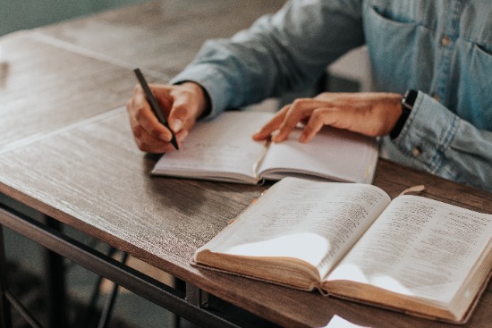 Man in personal study of the Bible, while also taking notes, as we learn more about the messages the Bible prophets share.