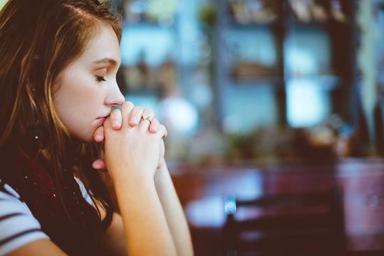 Woman praying as we study in Ephesians 6-18 how prayer allows us to communicate with God and to rely on Him for strength.