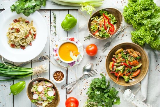 Dishes of vegetarian food surrounded by green vegetables