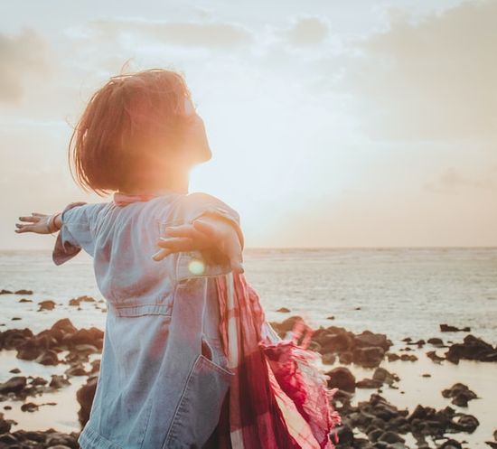 A woman at the ocean, enjoying the fresh air and sunshine, which are two Adventist principles of healthy living