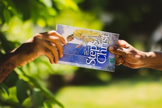 Someone handing out the book Steps to Christ as a way of sharing God's love