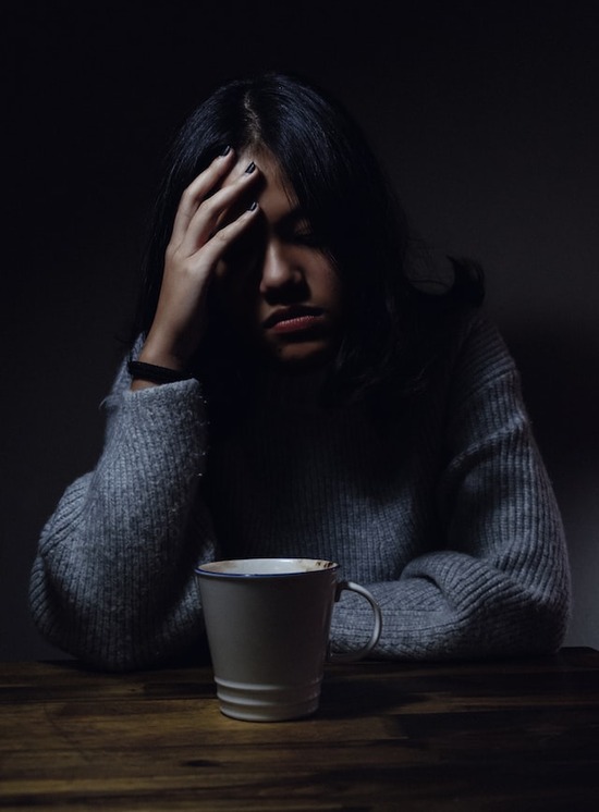 A woman with her hand on her head as she prays to God in difficult times