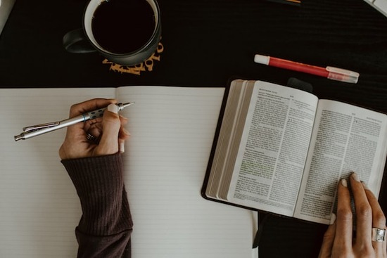 A person studying the Holy Scriptures and taking notes, inspired by reading Ellen White's writings