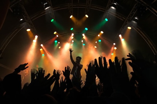 People raising their hands for a music artist, symbolizing the human tendency to idolize and worship other humans