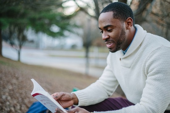 A man sitting on a park bench and reading a devotional book