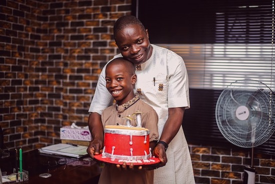 A Christian father holding a cake for his son and embracing him