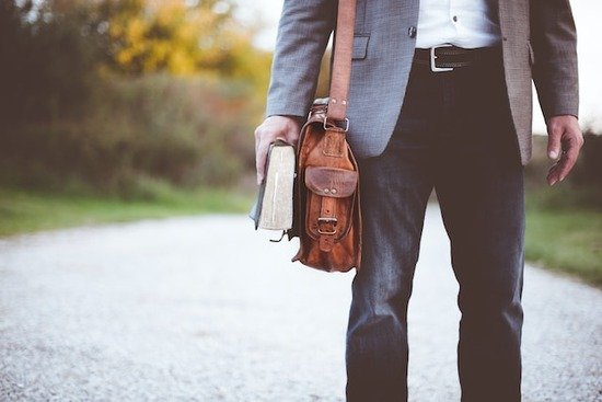 A man walking on a road carrying a Bible